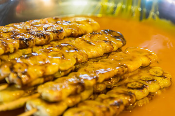 Grilled Banana with coconut source in plate, Roasted Banana on charcoal. Dessert of Thailand.