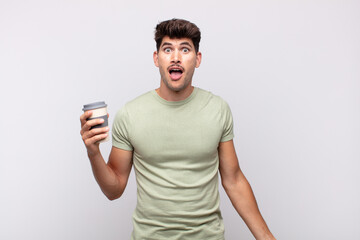 young man with a coffee looking very shocked or surprised, staring with open mouth saying wow