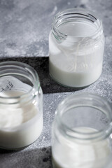 Dairy-free greek yogurt kefir with coconut milk in glass jar on gray background close-up. Healthy probiotic drink