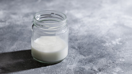 Dairy-free greek yogurt kefir with coconut milk in glass jar on gray background. Healthy probiotic drink