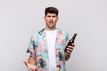 young man with a beer looking angry, annoyed and frustrated screaming wtf or what’s wrong with you
