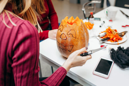 Young people cut and painting halloween pumpkin 