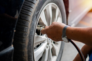 Hand of a young male holding the pipe to checking air pressure and filling the Nitrogen air in the tires of his car in a service station, Take Close up and selective focus on hand. Blurred background.