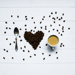 Heart shape made from coffee beans with spoon and cup of coffee, spelling I love coffee.