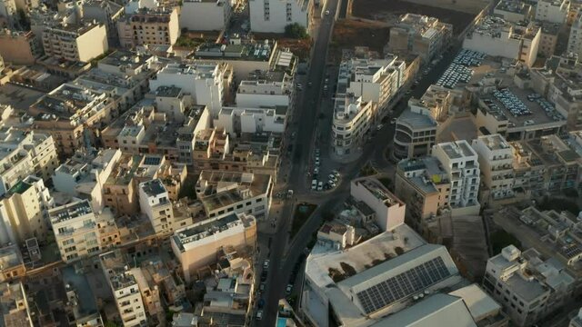 Road going through Malta Island City with Beige Brown Buildings in Sunlight, Aerial Drone Crane up