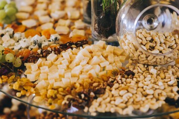 Close up of various types of cheese, nuts and peanuts on a banquet table.