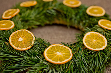 Fototapeta na wymiar Christmas wreath of fir branches decorated with dried orange slices. Advent ornaments.