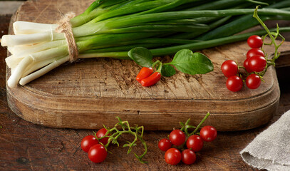 red ripe cherry tomatoes and a bundle of green onions tied with a rope