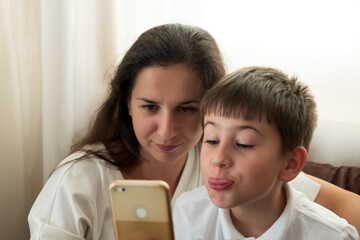 Mother with boy using smartphone for chat with friends or snapping selfie. Education technology. Soft focus