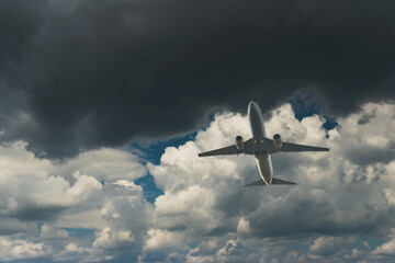 Fototapeta na wymiar Commercial airplane flying through clouds in dramatic sky. Travel concept