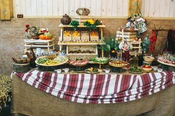 Decorated catering table in the Ukrainian rustic style with different food snacks and appetizers.