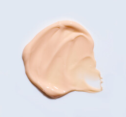 Swatch of beige facial cream on a grey background