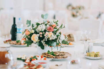 Bouquet with roses, eustoma and eucalyptus leaves. Wedding table setting decorated with flowers.