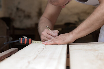 Male carpenter working with wood material in a garage.