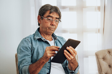 Senior man working on digital tablet at home