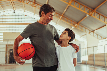 Latin grandfather and grandson playing basketball on the court