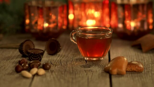 Homemade Christmas mulled wine punch with gingerbread, nuts and sweets on wooden rustic table in 4K VIDEO. Burning candles in background. Traditional autumn and winter hot drink. Close-up.