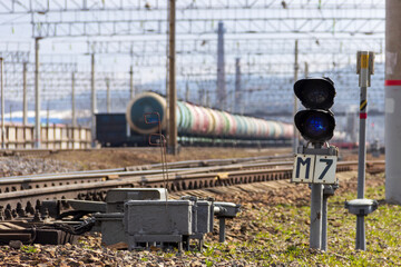A semaphore with a blue signal against the background of railway tank cars with oil products at a...