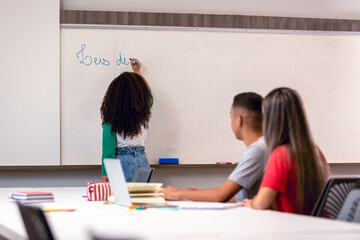 Grupo de alunos em sala de aula ouvindo a professora