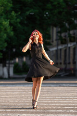 Fototapeta premium happy girl with pink hair walking in the city, crossing the road and talking on her mobile phone