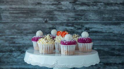 delicious cupcakes with white cream decorated with ripe strawberries on a gray blue background.