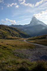 Road in the grass with the Matterhorn in the background on a summer evening in the Valais Alps of Switzerland. 
