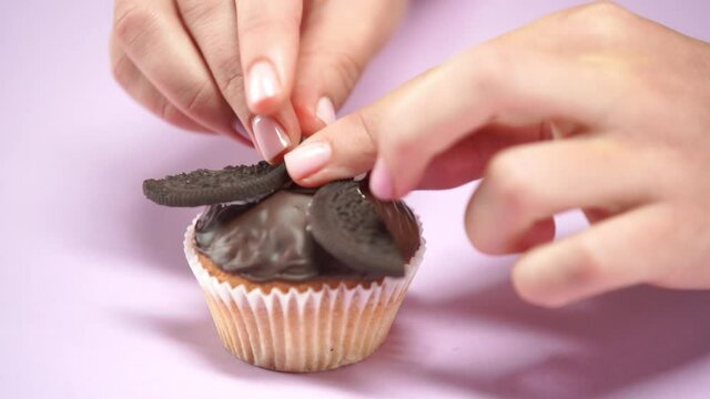 cropped view of woman putting sweet decorative eyes on chocolate muffin