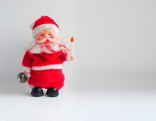Toy Santa Claus with a candle and a bell. Christmas background with a copy space