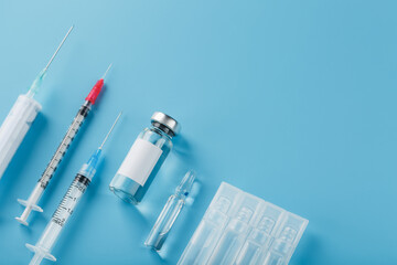 A set of medical syringes and ampoules with medicines and vaccines in a row on a blue background.