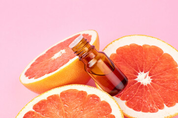 Grapefruit pure essential oil with fresh grapefruit halves on pink background. Beauty and health...