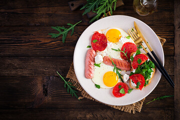English breakfast - fried eggs, sausages, tomatoes and feta cheese. American food. Top view, overhead, copy space