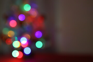 Die bunten und verschwommenen Lichter eines kleinen und weißen Weihnachtsbaumes stehend auf einem...