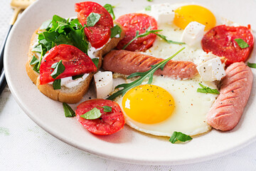 English breakfast - fried eggs, sausages, tomatoes and feta cheese. American food.