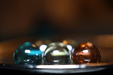 Gro&szlig;e und gl&auml;nzende Glaskugeln in verschiedener Anzahl auf einem braunen Holztisch. Sie repr&auml;sentieren die vier oder f&uuml;nf Elemente.