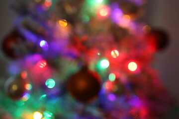 Die bunten und verschwommenen Lichter eines kleinen und wei&szlig;en Weihnachtsbaumes stehend auf einem roten Tuch.