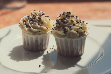 Appetizing cupcakes with white cream decorated with balls of confectionery powder