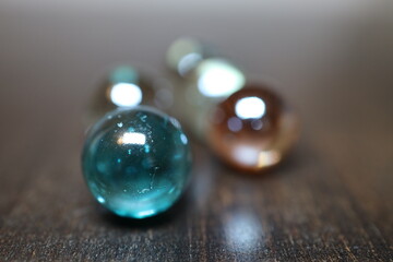 Gro&szlig;e und gl&auml;nzende Glaskugeln in verschiedener Anzahl auf einem braunen Holztisch. Sie repr&auml;sentieren die vier oder f&uuml;nf Elemente.