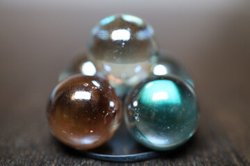 Große und glänzende Glaskugeln in verschiedener Anzahl auf einem braunen Holztisch. Sie repräsentieren die vier oder fünf Elemente.