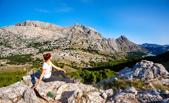 Woman hiker sitting on the rock and enjoying view to the mountain Puig Major, Mallorca island, GR 221