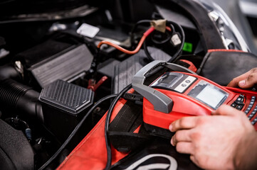 Hands of car mechanic checks auto battery charge