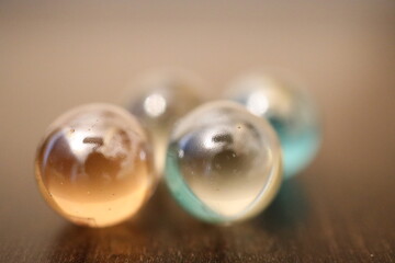 Große und glänzende Glaskugeln in verschiedener Anzahl auf einem braunen Holztisch. Sie repräsentieren die vier oder fünf Elemente.
