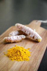 Turmeric root and spice powder on a cutting board