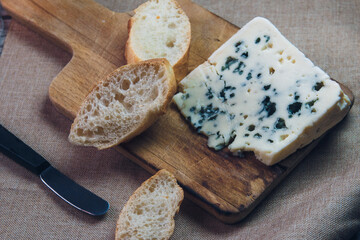 Queso Roquefort con trozos de pan sobre tabla de picar