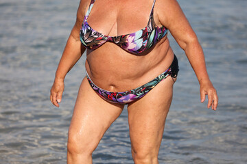 Fat woman in a swimsuit on the seashore.