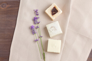 natural spa cosmetics. a simple composition of different handmade soaps and a mini lavender bouquet on a beige fabric background. copy space, flat lay