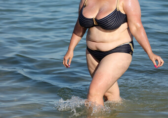 Fat woman in a swimsuit on the seashore.