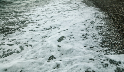 Stone pebbles on the seashore washed by a wave of water.