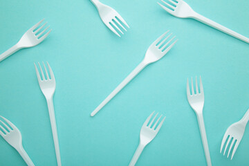Many plastic forks on a blue background.