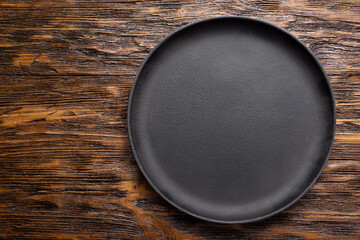 Empty cast iron frying pan on wooden culinary background. Space for text.