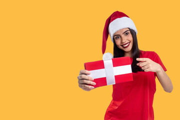 Woman with Christmas hat holding a gift, isolated on yellow background